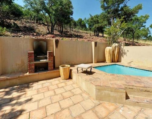 un patio con chimenea y piscina en Lodge Lucanus en Bela-Bela