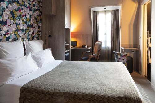 a hotel room with a large bed and a desk at Hôtel Regent's Garden - Astotel in Paris
