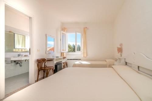 a white bedroom with a bed and a desk at Hotel 3 Botti in Baja Sardinia