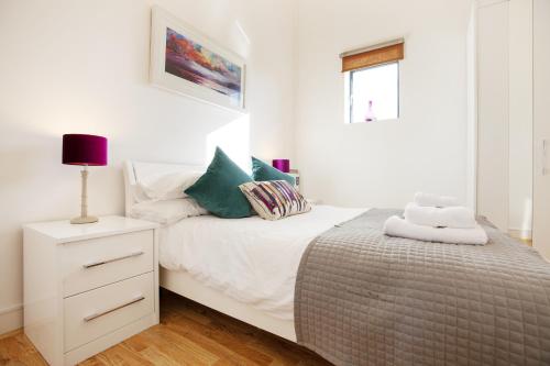 a white bedroom with a bed and a night stand at Urban Living's - The Wren in Oxford