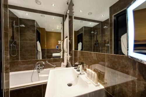 a bathroom with a sink and a tub and a mirror at The Pavilions Amsterdam, The Toren in Amsterdam