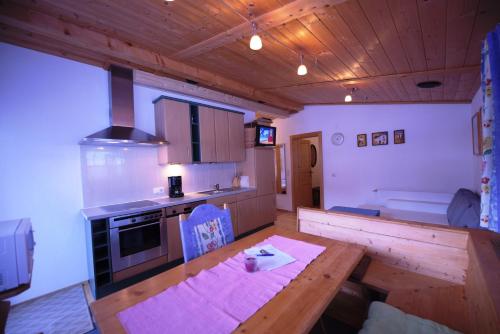 a kitchen with a wooden table and a wooden ceiling at Appartements Oberdorfer in Landeck
