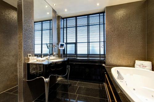 a bathroom with a tub and a sink and a bath tub at The Pavilions Amsterdam, The Toren in Amsterdam