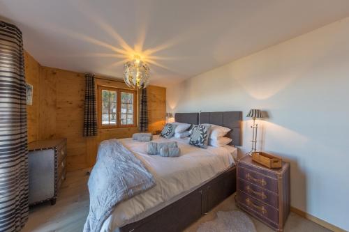 a bedroom with a large bed and a chandelier at Chalet Riquet - Ski/in-out - Jacuzzi in Nendaz