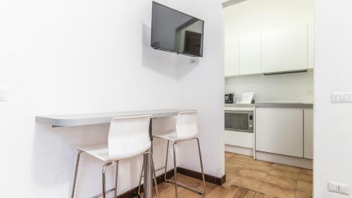 una cocina con armarios blancos y una barra con taburetes en Italianway-San Maurilio 20 studio en Milán