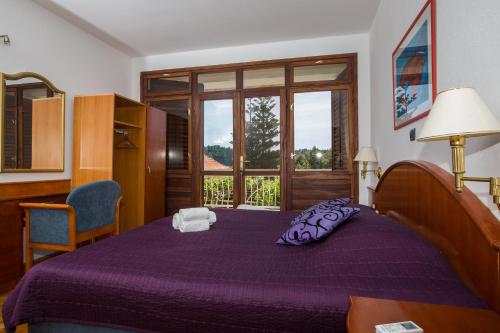 a bedroom with a purple bed and a window at apartments kralj1 in Cavtat