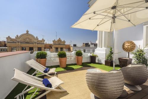 a patio with chairs and an umbrella on a roof at Boutique Hotel H10 Villa de la Reina in Madrid