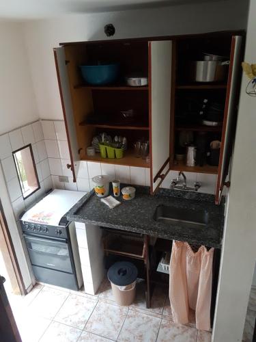 uma pequena cozinha com um lavatório e um fogão em Sol e Cia casa de temporada em Caraguatatuba