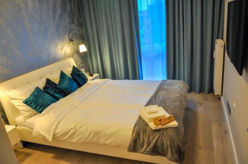 a bedroom with a white bed with blue pillows at Verde Apartment in Zielona Góra