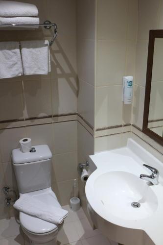 a bathroom with a white toilet and a sink at Hotel Kleopatra in Alanya
