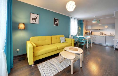 ein Wohnzimmer mit einem gelben Sofa und einer Küche in der Unterkunft Apartamenty Sun Seasons 24 - Villa Avangarda in Szklarska Poręba