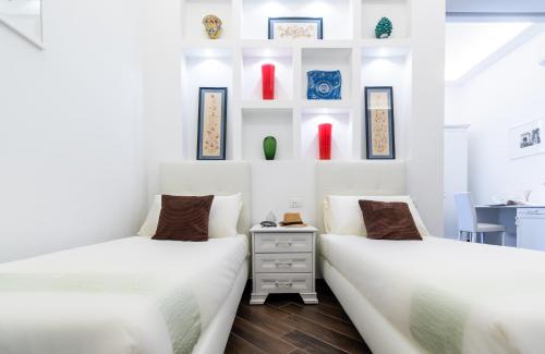 two beds in a room with white walls at Suites Sorrento Elegance in Sorrento