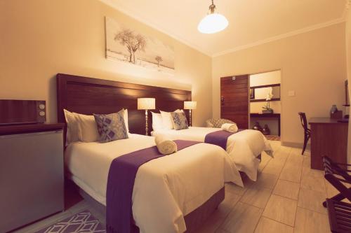 ein Hotelzimmer mit 2 Betten und einem TV in der Unterkunft Three Olives Guesthouse in Centurion