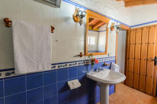 a blue tiled bathroom with a sink and a mirror at Casa Jardín del Olivar con Piscina privada in Alcaucín