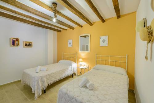 two beds in a room with yellow walls at Casa Jardín del Olivar con Piscina privada in Alcaucín