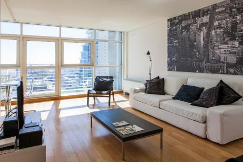 a living room with a white couch and a table at RENT4REST LISBON PARQUE DAS NAÇÕES 17Th FLOOR RIVER VIEW in Lisbon
