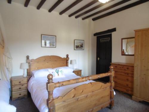 1 dormitorio con cama de madera y tocador de madera en The Old Mill and Cottage en Matlock