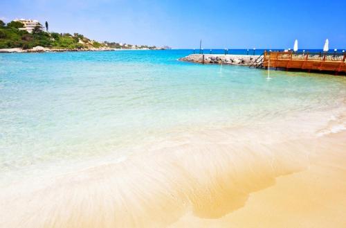 een strand met blauw water en een houten pier bij ADA Hotel Superb Beachfront Location ! in Kyrenia