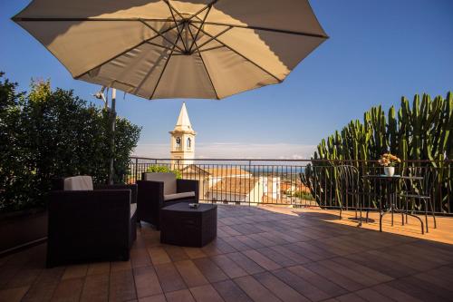 a patio with an umbrella and chairs and a table at House Etna View in Mascali