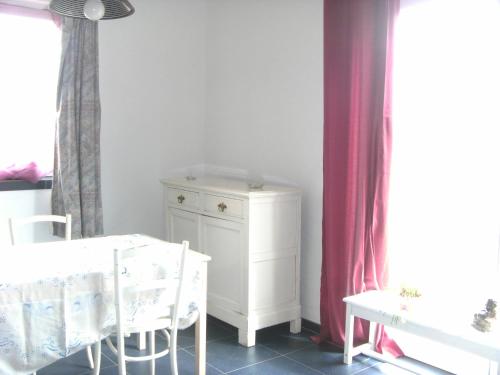 uma sala de jantar com uma mesa e um armário branco em Ferme Lenfant Rez em Ville-Pommeroeul