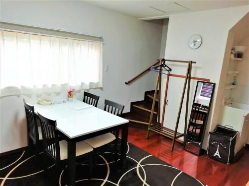 a dining room with a table and chairs and a staircase at Panda Stay Okayama in Okayama