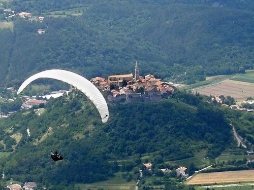 a person is flying a parachute over a village at Sweet room with a terrace in Roč