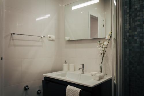 Un baño blanco con lavabo y espejo. en Aguda Golf Vita, en Arcozelo