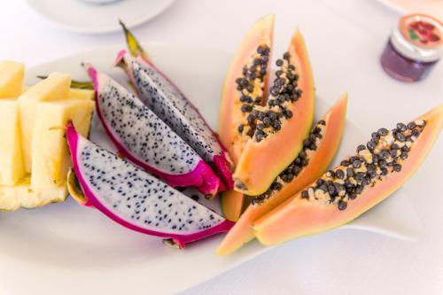 Un plato blanco con rodajas de papaya y otras frutas. en Grand Hotel Costa Brada, en Gallipoli