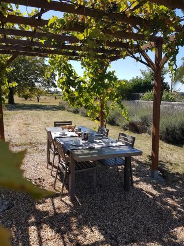 le domaine de bellevue في Tanzac: طاولة خشبية مع كراسي تحت البرغولية