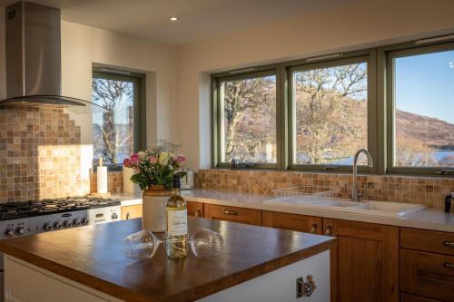 uma cozinha com um balcão com um lavatório e janelas em The View em Isleornsay