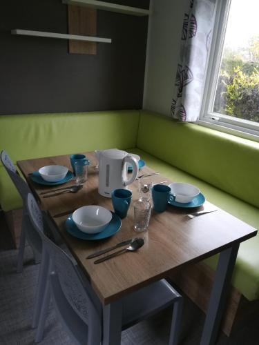 a wooden table with plates and utensils on it at Camping Loisirs Des Groux in Mousseaux-sur-Seine