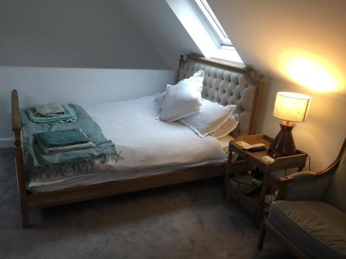 a bedroom with a bed with a lamp and a chair at Oliver's Studio at Oliver's Yard in Shipton under Wychwood