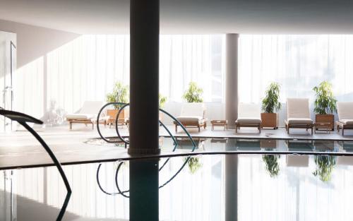 a lobby with chairs and a pool in a building at Schgaguler Hotel in Castelrotto