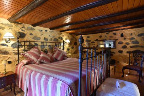 1 dormitorio con 1 cama en una habitación con paredes de piedra en Casa Rural El Borbullón, en Teror
