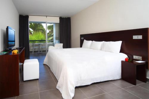 a bedroom with a large white bed and a television at Mahogany Hotel Residence & Spa in Le Gosier