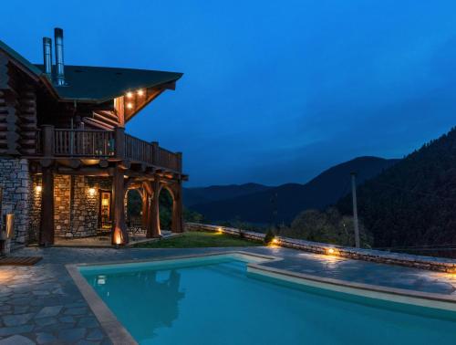 uma casa com piscina à noite em Mythica Chalet em Karpenision