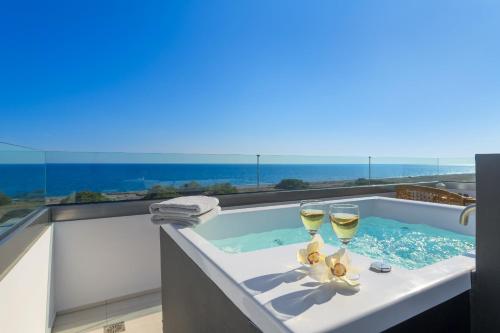 a hot tub with two glasses of wine at Albatross Beach Front Villas in Gennadi