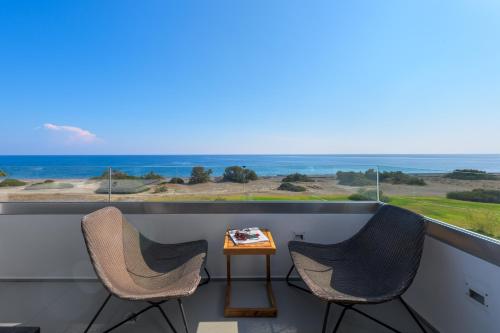 two chairs and a table on a balcony with a view of the ocean at Albatross Beach Front Villas in Gennadi