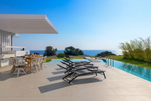 a row of chairs and tables next to a swimming pool at Albatross Beach Front Villas in Gennadi