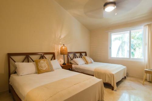 deux lits dans une chambre avec une fenêtre dans l'établissement Rosa Del Desierto | 3BR | Condo | Puerto Aventuras, à Puerto Aventuras