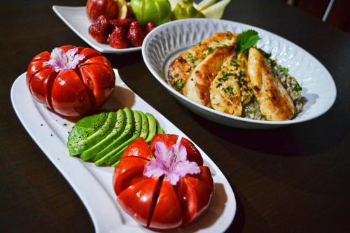 three plates of food on a table with tomatoes and vegetables at El Rincon Eco Hotel in Los Ángeles