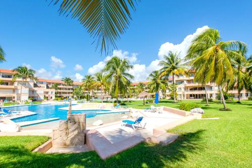 - une piscine avec des palmiers et des bâtiments dans l'établissement Rosa Del Desierto | 3BR | Condo | Puerto Aventuras, à Puerto Aventuras