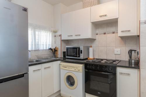 a kitchen with a washing machine and a microwave at Sands Beach Breaks Umdloti Beach View in Umdloti