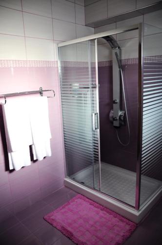 a pink bathroom with a glass shower with a pink rug at Haven Beach in Faliraki
