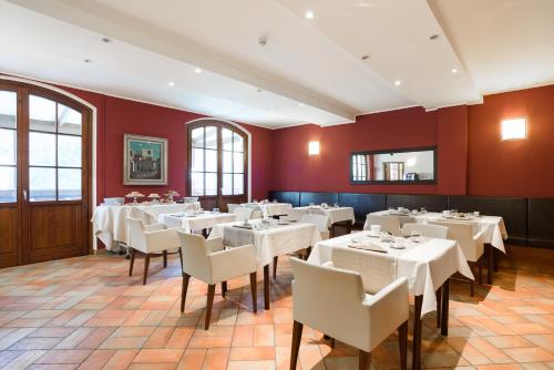Vaprio dʼAddaにあるCountry Hotel Castelbarcoの白いテーブルと椅子、赤い壁のレストラン
