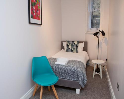 a small bedroom with a bed and a blue chair at Soho Chambers by Indigo Flats in London