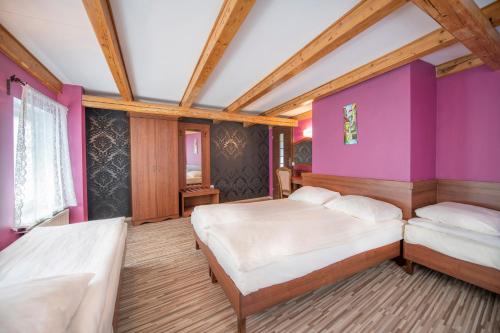 a bedroom with two beds and a purple wall at Dworek Galosa in Stronie Śląskie