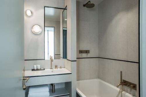 a bathroom with a sink and a tub and a mirror at Maison Armance - Esprit de France in Paris