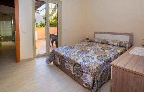 a bedroom with a bed and a door to a patio at Casa del Melograno 40 in Roccalumera