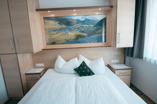a bedroom with a white bed with a painting on the wall at Apart Bauernhof ,,Becka Hof´´ in Nauders